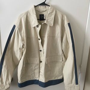 White denim jacket with blue streak along sleeve and waistline.
